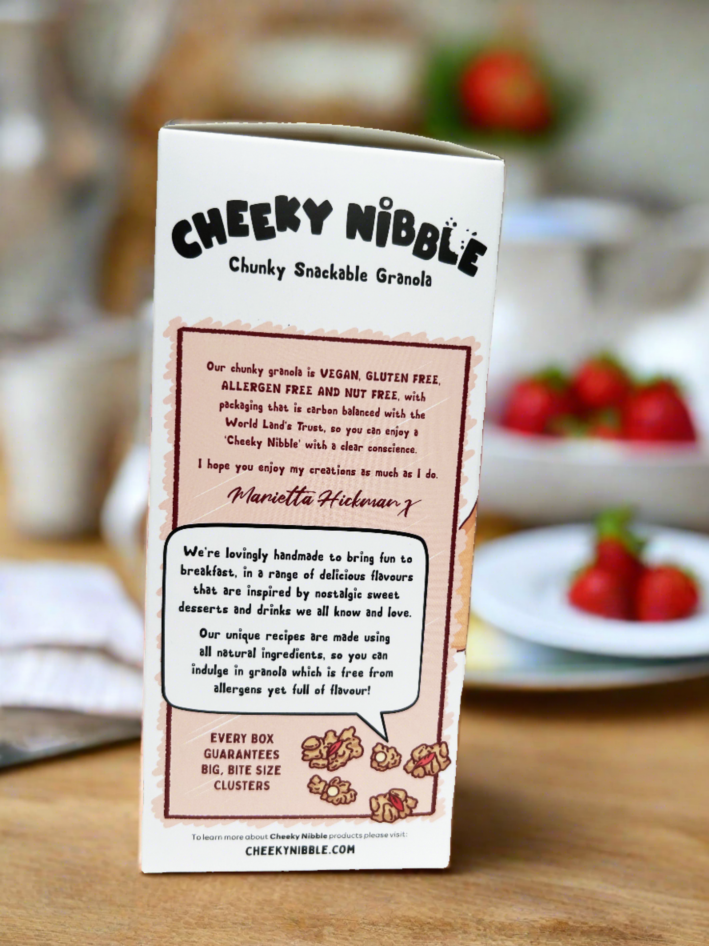 Each chunk is depicted with intricate detail, highlighting its hearty texture and diverse blend of ingredients, including oats, nuts, seeds, and dried fruits. The background may feature a rustic kitchen setting or a lush natural landscape, evoking a sense of wholesome goodness and culinary craftsmanship. Text on the box may describe the crunchy, flavorful nature of the granola, enticing consumers with promises of a satisfying breakfast or snack option rich in taste and nutrients.